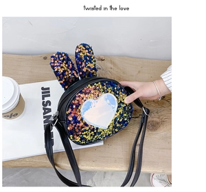 Detail of sequin bunny ears on a black glitter shoulder bag for girls on a wooden bench