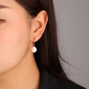 Elegant natural Baroque pearl drop earrings with gold hooks worn by a female model