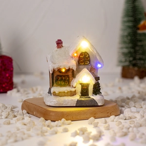 Close-up of lighted miniature Christmas snow house with festive LED and resin details