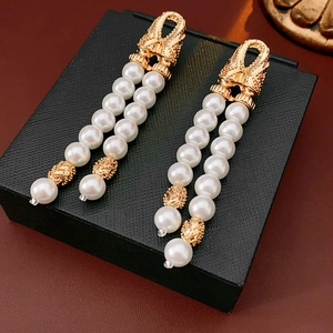 Close-up of vintage golden pearl tassel earrings on a textured black jewelry box display