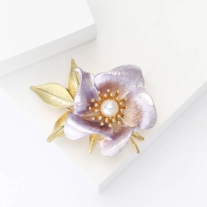 Elegant purple enamel daffodil brooch with pearl center and gold stem on white pedestal