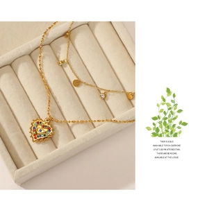 Close-up of gold 14K layered heart and eye pendant necklace on beige jewelry box