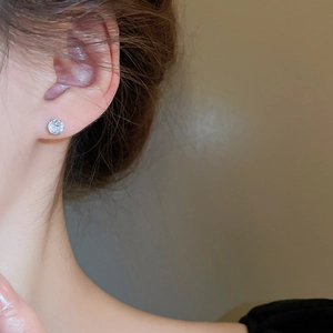 Close-up of a model wearing a six-prong round zircon stud earring in silver metal finish