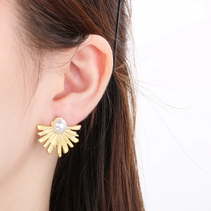 Vintage sunburst stainless steel stud earrings with central pearl on model's ear