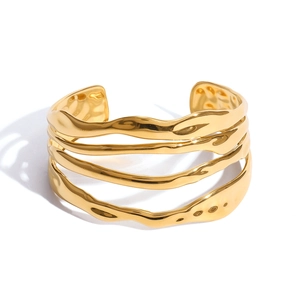 Close-up of golden multi-layer open bangle with wavy texture and high-polish finish