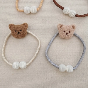 Detail of plush bear curtain tiebacks with imitation pearls in beige and brown tones
