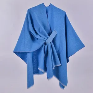 Close-up of royal blue shawl featuring knitted texture, fringe edges and crossover design