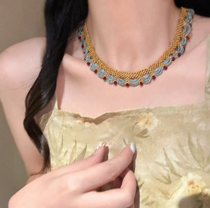 Détail d'un ras du cou tissé main avec perles de cristal bleues et rouges au cou