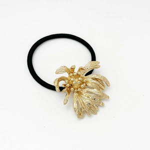 Close-up of golden metal flower charm and black elastic ponytail holder hair ring