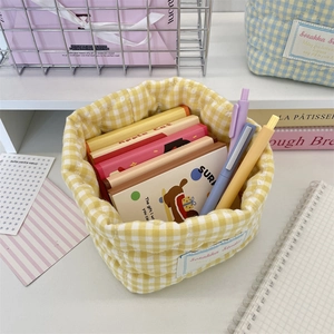 Primer plano de una cesta de tela a cuadros amarillos para organizar papelería de escritorio