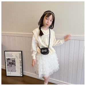 Detail of beige knitted vest with pearl bow pattern and layered mesh tutu skirt for girls