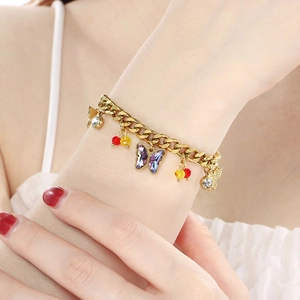 Close-up of a gold butterfly charm bracelet with colorful crystals on a model's wrist