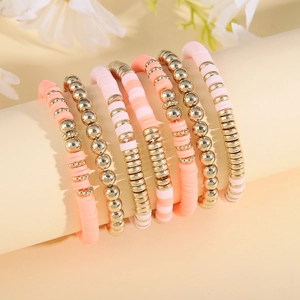 Detail of 7-piece bohemian pink heishi clay bead and gold metal stretch bracelet set