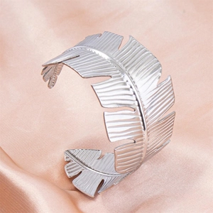 Silver tropical leaf cuff bracelet in stainless steel on champagne silk background