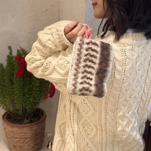 Detail of plush zig-zag storage pouch with pink strap held against beige sweater