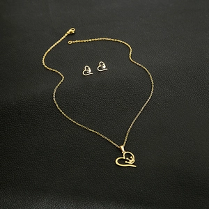 Detail of gold-plated hollow heart and crown necklace set on black leather texture