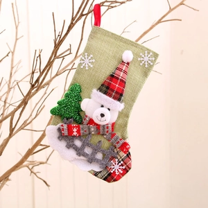 Hanging green Christmas stocking with cute bear decor and red plaid snowflakes pattern