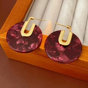 Detail view of round burgundy tortoiseshell acetate earrings with gold-plated U-shaped studs