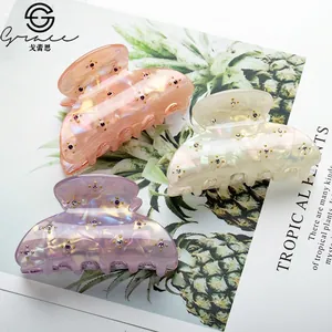 Three pearl-lustre hair claw clips with rhinestones in peach, white, and lavender