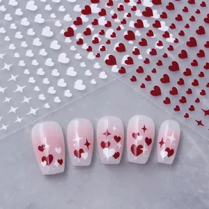 Detail of red and white heart nail stickers with star motifs on pink gradient nails