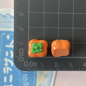 Vista macro di ciondoli a forma di cachi in resina da 1,5 cm su tappetino graduato
