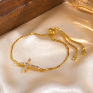 Detail of gold box chain cross bracelet with pavé zircons on silk background