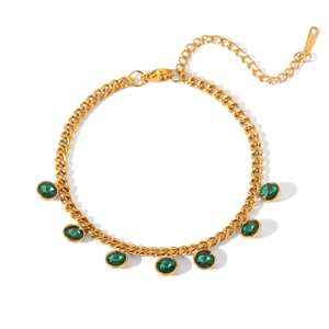 Détail d'un bracelet en acier doré avec six zircons verts ronds et détails de glands