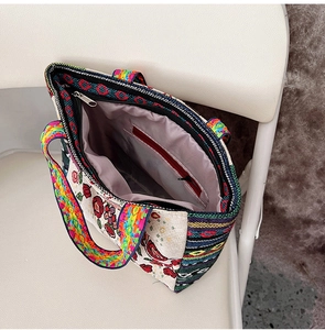 Close-up of floral embroidery detail and woven handles on ethnic canvas tote bag