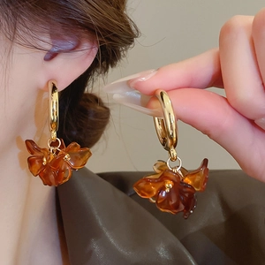 Detailed view of amber flower drop earrings with golden hoops worn for style