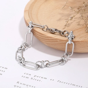 Detailed view of silver knot design bracelet on wooden tray with rustic dried floral accents
