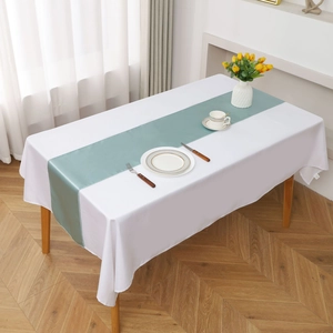 Close-up of light green satin table runner on white cloth for wedding decor