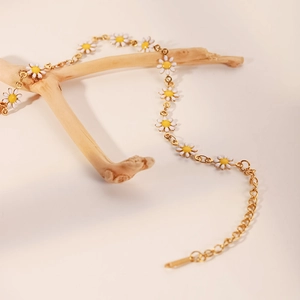 Detalle de margaritas blancas en una cadena de acero dorado sobre una rama de madera