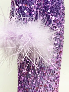 Détail de tissu à paillettes mauves avec bordure en plumes d'autruche sur une robe