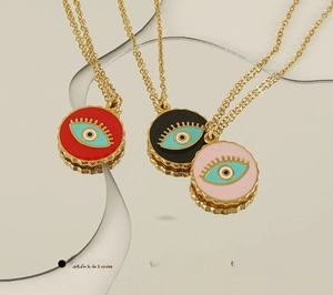 Detail of 18K gold-plated Evil Eye necklace with red, black, and pink enamel pendants