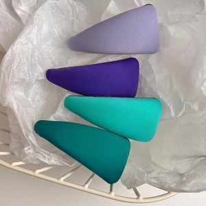 Close-up of four colorful fabric-wrapped triangle hair clips in purple and green shades