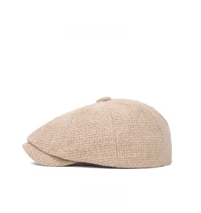 Side view of beige knitted newsboy cap showing textured fabric and top button detail
