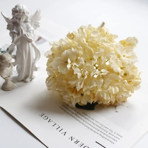 Detailed close-up of cream vintage faux hydrangea atop a magazine for home decoration