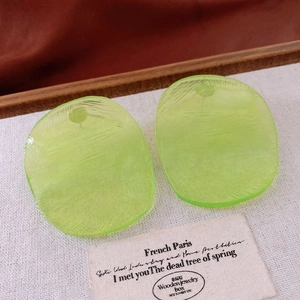 Macro detail of neon green resin geometric earring with brushed texture and polished finish