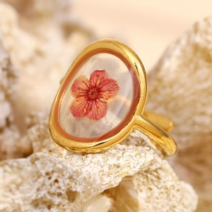 Macro d'une bague plaquée or 18 carats avec une véritable fleur rouge séchée