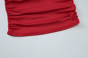 Détail du haut rouge asymétrique montrant les fronces latérales et les doubles coutures