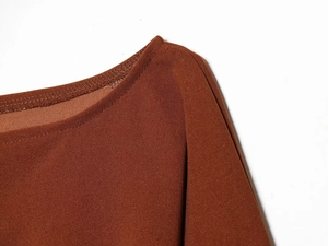 Detailed close-up of brown knit fabric texture and shoulder stitching on the top
