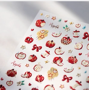 Vue macro de stickers ongles 3D en relief avec motifs de pommes rouges et nœuds