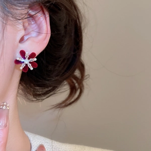 Macro detail of red flocked flower earring with zircon center and pearl petal tips
