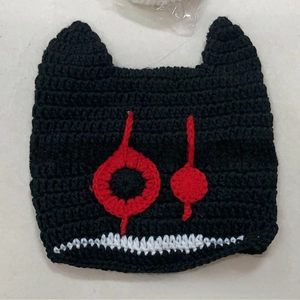 Close-up of black crochet knit beanie with devil cat ears and red eye embroidery
