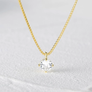 Macro view of gold box chain necklace featuring a classic four-prong set round zircon stone