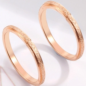 Pair of rose gold stainless steel rings with frosted matte texture and shimmering finish
