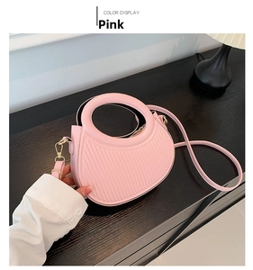 Close-up of pink saddle bag featuring vertical striped texture and golden metal hardware