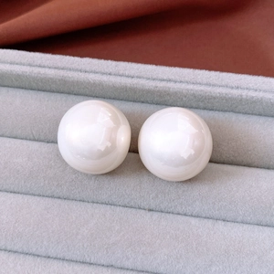 Close-up of large round white pearl earrings in a grey velvet jewelry display box