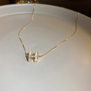 Elegant gold chain necklace with a white mother-of-pearl H-shaped pendant on a plate