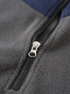 Close-up of premium zipper and textured gray-navy fleece stitching on tactical jacket